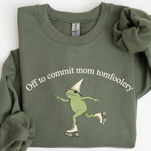 Puede incluir: Una taza de cerámica blanca con un asa negra y el texto "But First, Coffee" en negro, con una fuente de estilo manuscrito. La taza está sobre una superficie blanca.