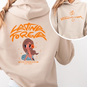 以下が含まれることがあります： 背面にオレンジ色の「LATINA FOREVA」という文字、髪に花をつけた女の子の漫画風イラスト、「COLOMBIANA EST. 2000」という文字がプリントされたベージュのフード付きスウェットシャツ。前面にはオレンジ色の「Tropiquita」という文字が描かれています。