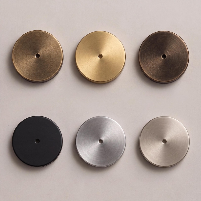 May include: Six circular metal cabinet knobs arranged in two rows of three. The top row features antique brass, brushed gold, and oil-rubbed bronze finishes. The bottom row includes matte black, brushed chrome, and satin nickel finishes.