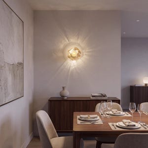 May include: A wall-mounted light fixture with a translucent, organic-shaped glass shade that emits a warm, glowing light, casting distinct, radiating light patterns across the surrounding neutral-toned wall surface.
