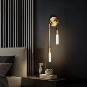 Könnte beinhalten: Eine goldene Wandleuchte mit zwei herabhängenden Glühbirnen. Die Glühbirnen sind aus mattem Glas und strahlen ein warmes, weißes Licht ab. Die Leuchte ist an einer dunklen Wand montiert.