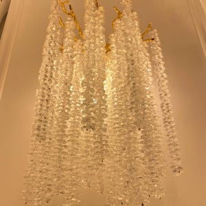 May include: A gold-toned metal wall sconce with cascading crystal beads. The sconce has a unique branch-like design and features a cluster of clear crystal beads hanging from each branch.
