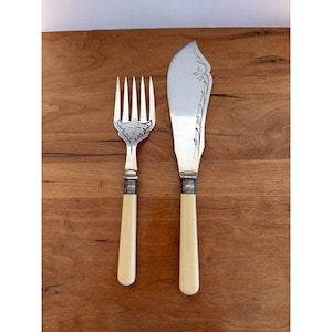 May include: A white ceramic mug with a black handle and the text "But First, Coffee" in a bold, black font. The mug is set against a blurred background, suggesting a cozy setting.