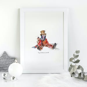 May include: A framed watercolour print of a character in a top hat and festive clothing. The artwork includes the text "Merry Christmas, we all". A silver star, candle, and decorations are in the foreground.