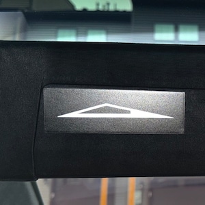 May include: A black car sun visor with a white triangle symbol that says "Lane Departure Warning" on a silver background.