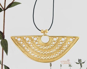 May include: A gold-toned, semi-circular pendant featuring an intricate filigree pattern of concentric circles and braided textures. The pendant is suspended from a thin black cord, secured by two small gold-toned beads at the top center.