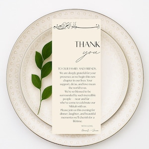 May include: A cream-colored place setting with a decorative rim, featuring a vertical card that reads "THANK YOU" in elegant script. The card includes text and a sprig of green leaves.