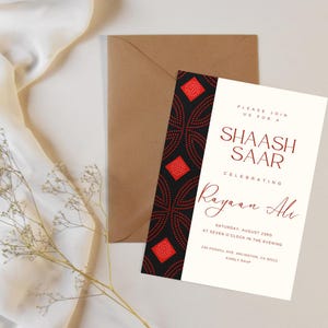 May include: An invitation suite featuring a cream-colored card with burgundy text and a patterned black and red border. The invitation includes the text "SHAASH SAAR" and "Rayaan Ali". A brown envelope and sprig of dried flowers are also present.