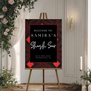 May include: A black and red welcome sign on a wooden easel. The sign reads "Welcome to Samira's Shash Saap" with the date July 11th, 2025, and location Manhattan, NY. The sign has a decorative red and black pattern.