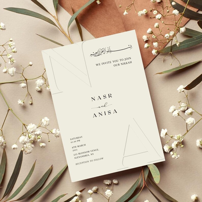 May include: A white wedding invitation with a minimalist design. The invitation features the names "NASR and ANISA" in a simple font. The date and time of the wedding are listed below, along with the location and a note that a reception will follow.