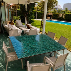 May include: A square outdoor dining table featuring a green mosaic tile top with a geometric pattern, supported by a black metal frame, surrounded by eight light-coloured chairs with metal frames on a matching green tiled patio floor.