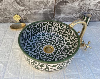 May include: A white ceramic sink with a green and white floral pattern. The sink has a brass faucet and drain.