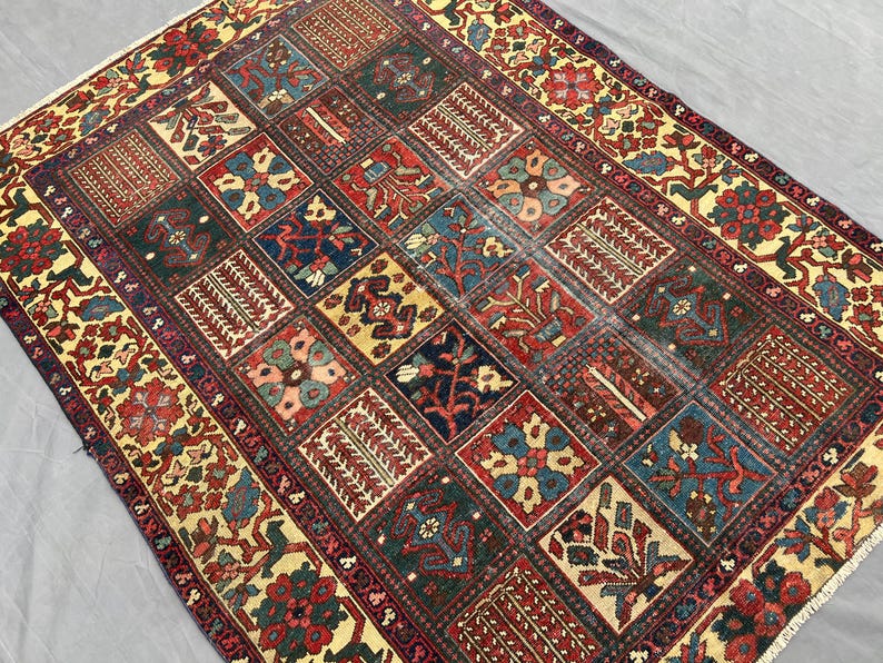 May include: A rectangular area rug featuring a grid of square panels, each containing distinct floral and geometric motifs in shades of deep red, navy blue, forest green, and cream. The border displays a repeating pattern of stylised plants.