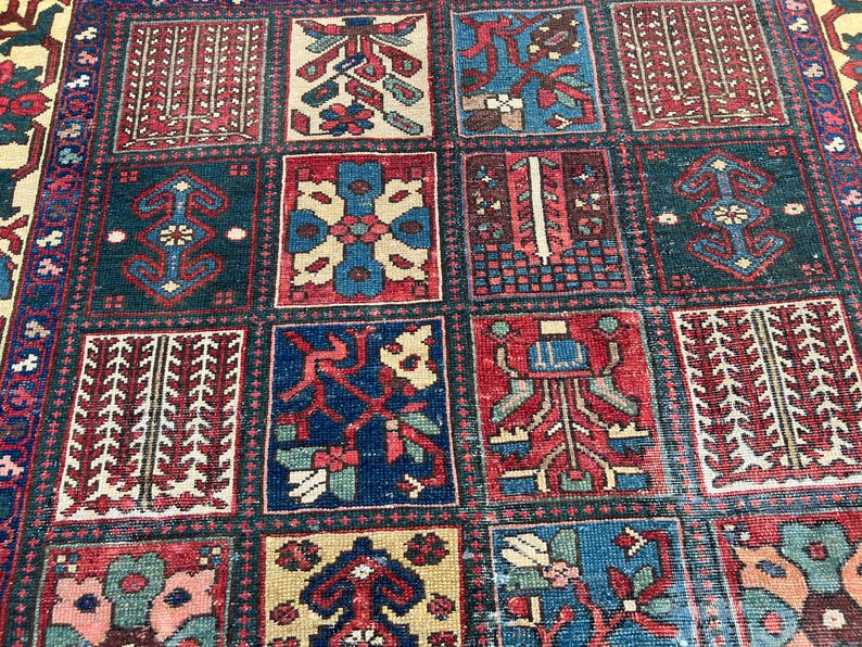 May include: A rectangular area rug featuring a grid of square panels, each containing distinct geometric and floral motifs in shades of deep red, navy blue, cream, and teal. The design is composed of repeating patterns within bordered sections.