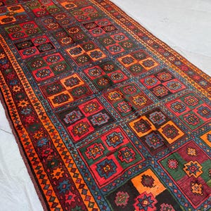 May include: A rectangular, patterned rug with a repeating geometric design. The rug features a color palette of red, orange, green, and blue. The border has a detailed, repeating pattern. The rug's design is symmetrical and intricate.