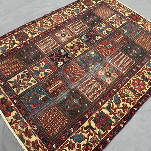 May include: A rectangular area rug featuring a grid of multicoloured square panels with intricate floral and geometric patterns. The border displays a repeating floral motif in red, green, and cream. The rug has short white fringe on the ends.
