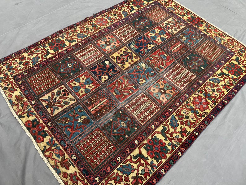 May include: A rectangular area rug featuring a grid of multicoloured square panels with intricate floral and geometric patterns. The border displays a repeating floral motif in red, green, and cream. The rug has short white fringe on the ends.