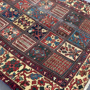 May include: A rectangular area rug featuring a grid of square panels, each containing distinct floral and geometric motifs in shades of deep red, navy blue, forest green, and cream. The border displays a dense pattern of flowers and vines.