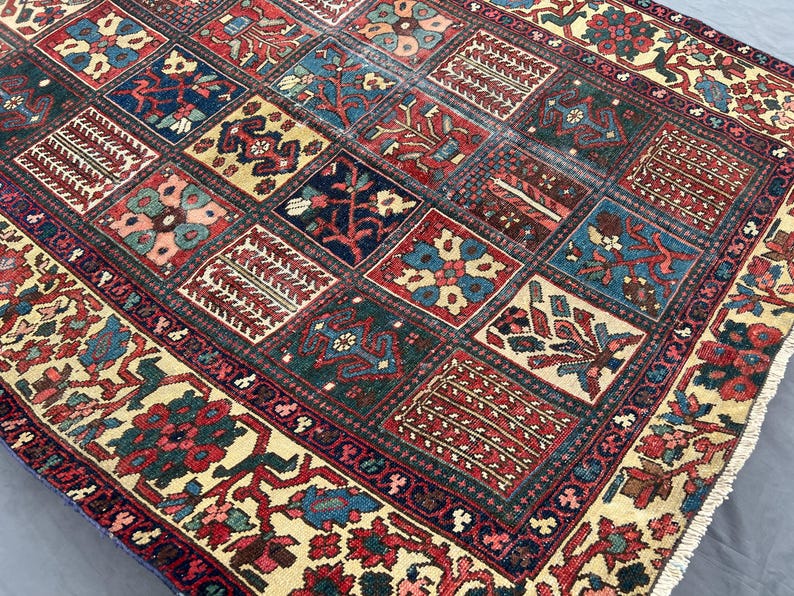 May include: A rectangular area rug featuring a grid of square panels, each containing distinct floral and geometric motifs in shades of deep red, navy blue, forest green, and cream. The border displays a dense pattern of flowers and vines.