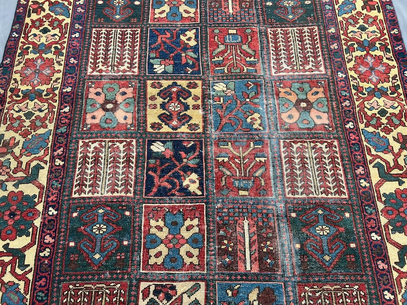 May include: A rectangular area rug featuring a grid of square panels, each containing distinct floral and geometric motifs in shades of deep red, navy blue, cream, and teal. The border displays a repeating pattern of stylised flowers and vines.