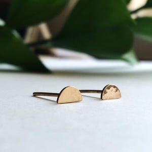 May include: A pair of gold half-circle earrings with a hammered texture.