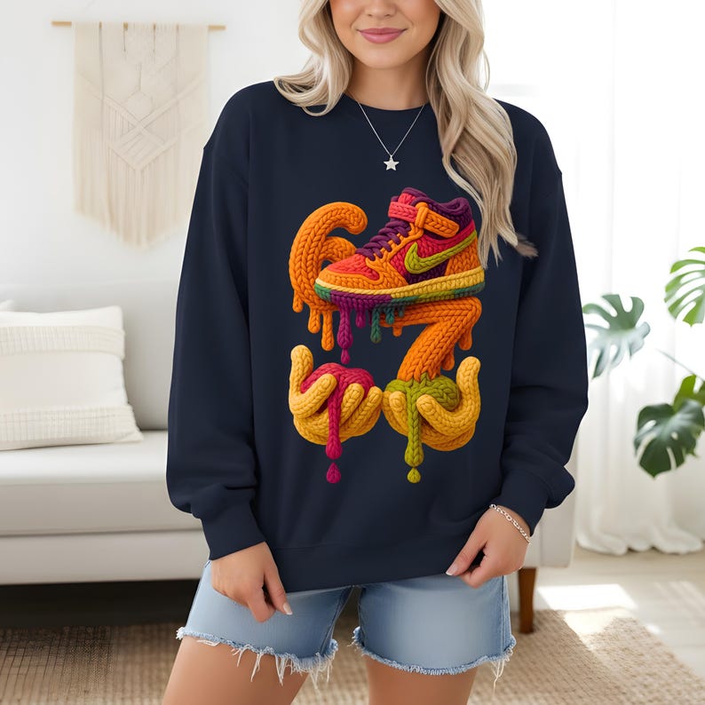 May include: Navy blue sweatshirt featuring a colorful, artistic design of a sneaker with dripping paint. The design incorporates orange, yellow, green, and purple hues, creating a vibrant and eye-catching graphic. The sweatshirt is a comfortable, casual style.