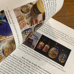 Op de afbeelding: Close-up van een pagina uit een boek over acryl gietkunst. De pagina toont een foto van een paar oorbellen gemaakt met deze techniek, en tekst over het proces. De tekst bevat de zin "Draadgewikkelde acryl gietvariatie".