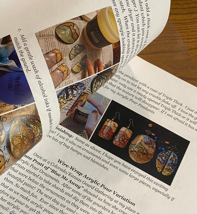 Op de afbeelding: Close-up van een pagina uit een boek over acryl gietkunst. De pagina toont een foto van een paar oorbellen gemaakt met deze techniek, en tekst over het proces. De tekst bevat de zin "Draadgewikkelde acryl gietvariatie".