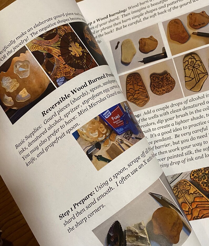 Op de afbeelding: Een boek met instructies voor het maken van omkeerbare gebrande houten hangers. Het boek bevat een lijst met benodigdheden, stappen voor het voorbereiden van de kalebas en het branden van het hout. Het boek bevat ook foto's van de afgewerkte hangers.