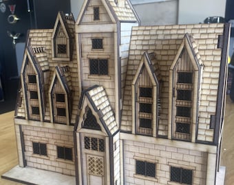 Könnte beinhalten: Ein Holzmodell eines gotischen Hauses mit einem spitzen Dach, mehreren Fenstern und einer detaillierten Haustür. Das Modell ist aus hellbraunem Holz gefertigt und hat ein strukturiertes Ziegelmuster.