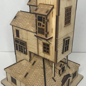 Könnte beinhalten: Detailliertes Holzmodell eines mehrstöckigen Hauses mit Schornstein. Das Haus verfügt über mehrere Fenster, ein Schindeldach und eine hellbraune Außenseite mit dunkleren braunen Zierleisten. Das Modell ist aus lasergeschnittenem Holz gefertigt.