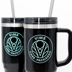 May include: Two black stainless steel travel mugs with black handles and a teal logo that says "VIMS CARE PACKAGED".  Each mug has a gray straw.
