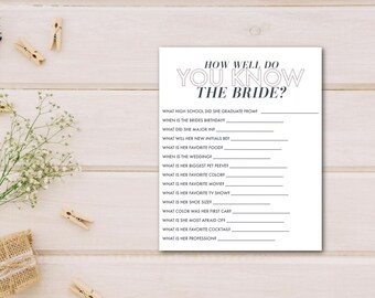 May include: A white card with the text "HOW WELL DO YOU KNOW THE BRIDE?" and fill-in-the-blank questions. The questions include "What high school did she graduate from?" and "What is her favorite cocktail?" Decorative elements include clothespins and flowers.