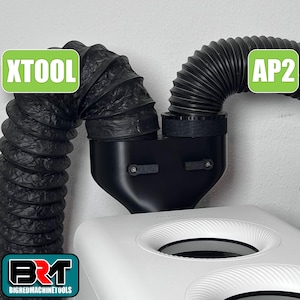 Puede incluir: Conductos flexibles negros y una unidad AP2 negra están conectados a una máquina blanca. Los textos "XTOOL" y "AP2" están en cuadros verdes. El logotipo de BIGREDMACHINETOOLS está en la esquina inferior izquierda.