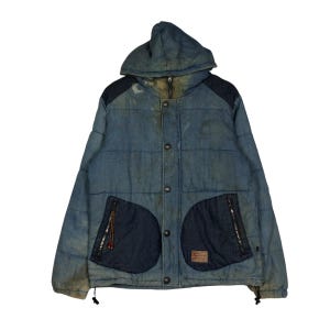 May include: A blue denim hooded puffer jacket featuring a quilted design, dark blue denim shoulder panels, and two large dark blue denim front pockets with zippered closures. The jacket includes a front button placket and a drawstring hem.