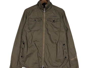 May include: A green zip-up jacket with a stand-up collar and two flap pockets on the front. The jacket has a zipper closure and a small logo on the right pocket that says "CHALLENGER LIFE".
