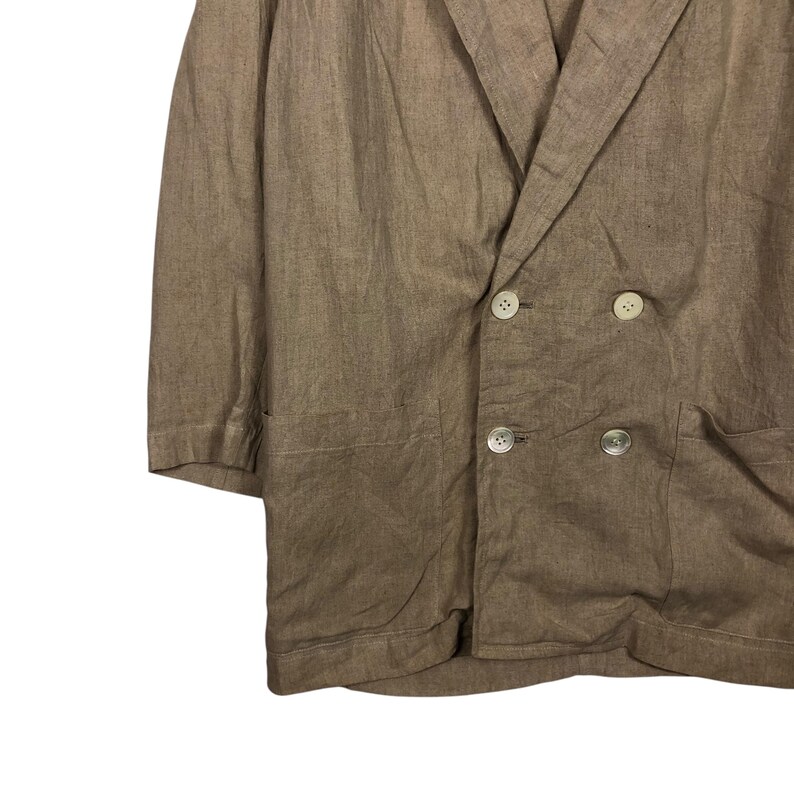K&ouml;nnte beinhalten: Ein brauner Blazer aus Leinen mit doppelreihigem Verschluss und zwei Taschen. Der Blazer hat eine lockere Passform und einen l&auml;ssigen Stil.