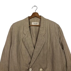 K&ouml;nnte beinhalten: Ein beiger Blazer aus Leinen mit doppelreihigem Verschluss und einem Etikett mit der Aufschrift "robe de chambre" auf der Innenseite.