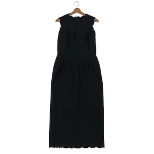 Puede incluir: Vestido negro sin mangas con escote y dobladillo festoneados, colgado de una percha de madera. El vestido tiene un corpi&ntilde;o ajustado y una falda recta, adecuado para ocasiones formales.