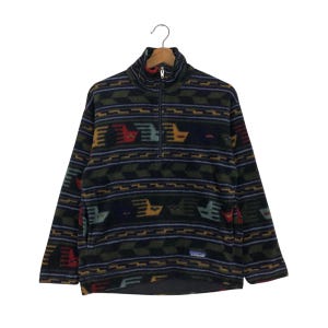 May include: A patterned fleece pullover with a half-zip closure. The design features geometric shapes and bird-like figures in shades of green, blue, yellow, and red. The pullover has long sleeves and a high collar. The Patagonia logo is visible.