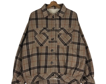 May include: A brown and black plaid flannel shirt with a sherpa lining. The shirt has two large pockets on the front and a button-up closure.