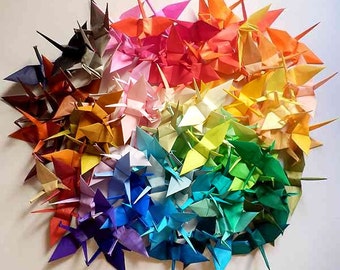 May include: A colorful arrangement of origami paper cranes in a rainbow pattern. The cranes are folded from paper in various shades of red, orange, yellow, green, blue, indigo, and violet.