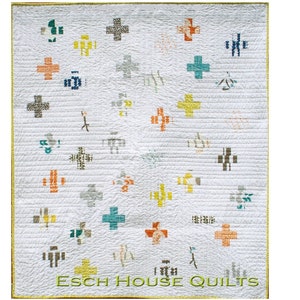 May include: A white quilt with a repeating pattern of colourful plus signs. The quilt is edged with a gold trim and has the text "ESCH HOUSE QUILTS" at the bottom.