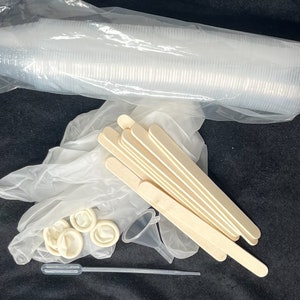 Może przedstawiać: Zestaw materiałów do rękodzieła, w tym stos przezroczystych plastikowych kubków, opakowanie jednorazowych rękawiczek, zestaw drewnianych patyczków, plastikowy lejek i przezroczysta plastikowa pipetka.