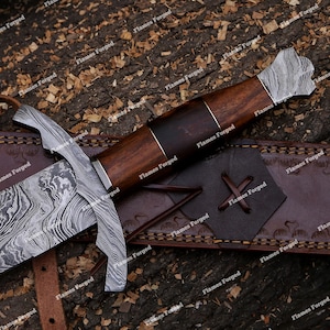 May include: A fixed-blade knife featuring a patterned Damascus steel blade and a bolster, paired with a dark brown wooden handle. The knife rests on a brown leather sheath with stitched detailing and a cross-laced accent on the front surface.