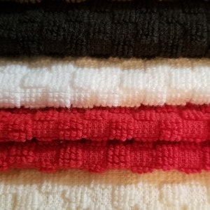 May include: A stack of six towels in various colors, including brown, black, white, red, beige, and brown. The towels are made of a soft, textured fabric.