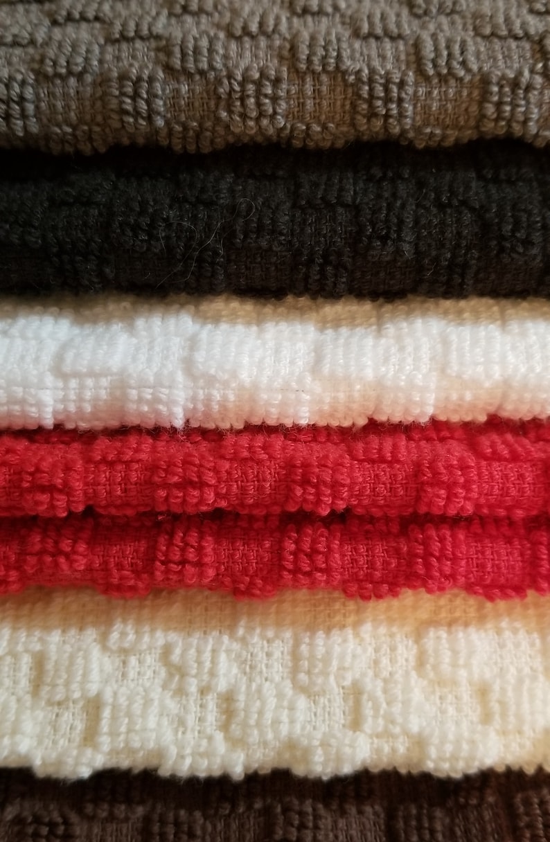 May include: A stack of six towels in various colors, including brown, black, white, red, beige, and brown. The towels are made of a soft, textured fabric.