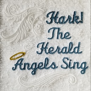 Pu&ograve; includere: Asciugamano bianco con ricamo blu che recita "Hark! The Herald Angels Sing". Un alone dorato &egrave; ricamato sopra le parole.