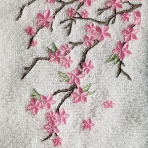 May include: White towel with embroidered pink cherry blossoms and brown branches.