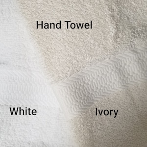 May include: Two hand towels, one white and one ivory. The ivory towel has a textured border. The text "Hand Towel" is written on the towels.